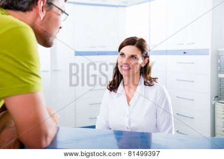 Doctors nurse with telephone in front desk making appointment with patient