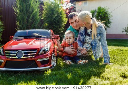 Young Family With A Child Playing On The Grass