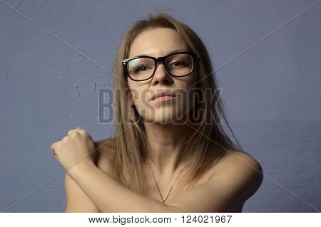 Closeup portrait of blonde woman with glasses isolated on blue background.