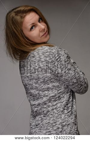 Portrait of a cheerful young woman standing back on gray background