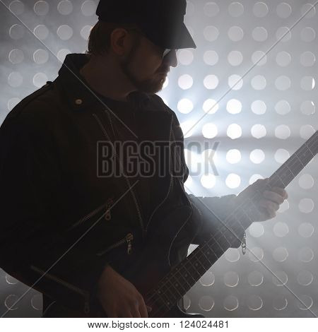 Bassist playing bass guitar in smoke. backlight