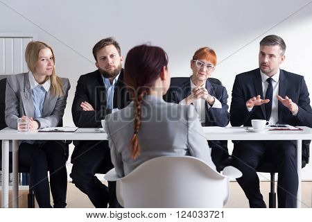 Young woman applying for a job in corporation. Talking in front of big commission