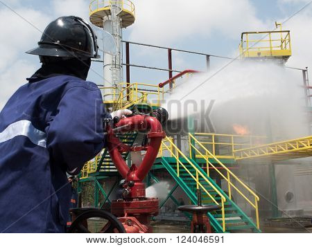Firefighters fighting fire with pressured water during training exercise. Fire fighter spraying a straight steam into fire off.
