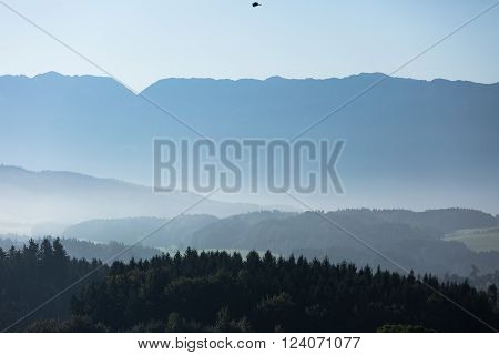 hilly foggy ground in front of amountain chain