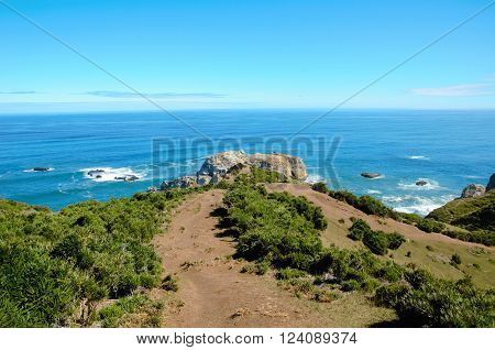 Coastal view onto the Muelle de las Almas with a clear blue sky and green hills