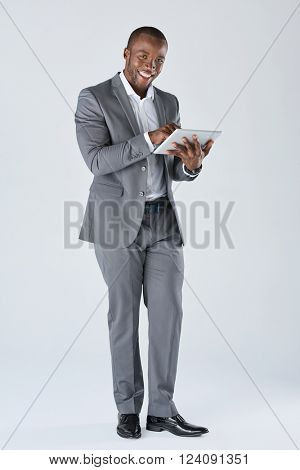 Full length portrait of positive friendly black  professional businessman with touchscreen tablet device in business suit isolated in studio