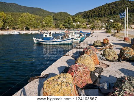 Multicolored fishing nets on the pier and fish boats in small harbour Skopelos island; Sporades; Greece