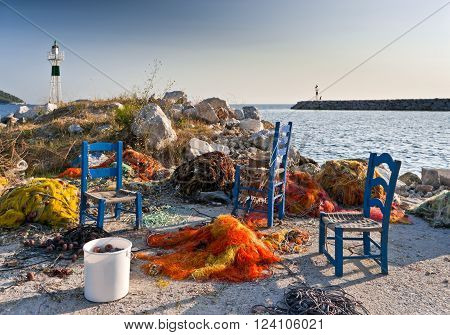 Multicolored fishing nets blue chairs on the pier and small lighthouses next to the sea Skopelos island; Sporades; Greece