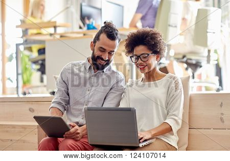 business, startup and people concept - happy creative team with laptop and tablet pc computer in office