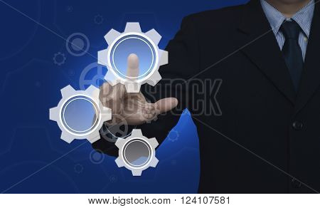 Businessman pressing gear icon with copy space over blue background