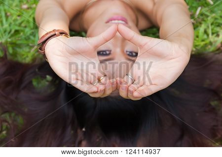 Young woman laying down and putting hands together in heart shape