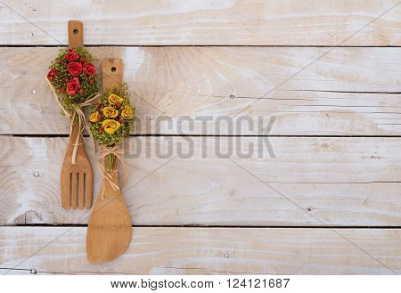 Wooden background with kitchen utencils decorated with flowers