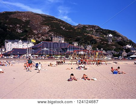 BARMOUTH, UK - AUGUST 6, 1995 - Holidaymakers on the beach with views towards the town and mountains Barmouth Gwyedd Wales UK Western Europe, August 6, 1995.