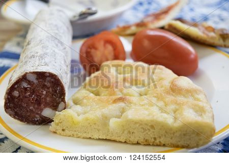 homemade flat cake filled with fresh tomatoes and salami