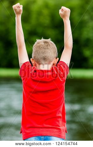 Self confident boy with raised fists celebrating a recent success or victory.