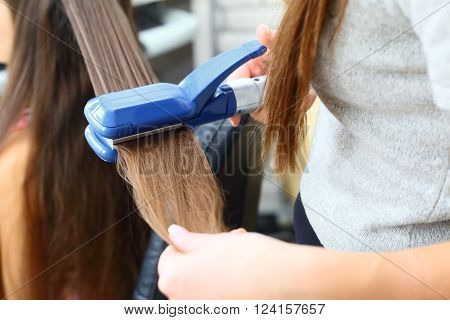 Straightener. Hairdresser hairstyle beautiful model using straightener.