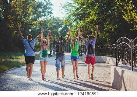 Three guys and two girls are having fun together and hold hands. Youth. Friends. Friendship. A young group of people. Summer rest. Summer
