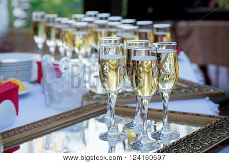 The Wedding Banquet. Banquet in the restaurant. Glasses of champagne in several rows on a mirror tray on the table with a white tablecloth.