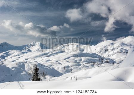 Winter panorama with snow covered slopes and dramatic sky. Komna, Slovenia.