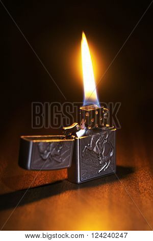Beautiful lighter on a wooden floor igniting the dark room