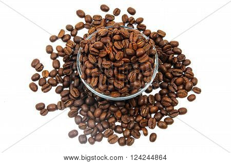 Scattered brown coffee beans inside and around glass jug