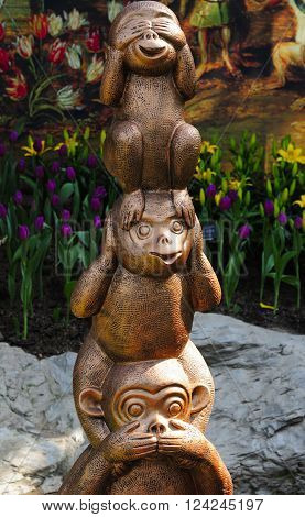 Three monkey statues representing see no evil hear no evil and speak no evil within a greenhouse at Chenshan Botanical Garden Shanghai China.