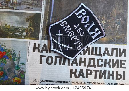 Kiev,Ukraine.FEB 20.ILLUSTRATIVE EDITORIAL.Chevron Ukrainian nazionalist battalion.Background - newspaper about West Frisian Museum stolen art . February 20,2016 in Kiev, Ukraine