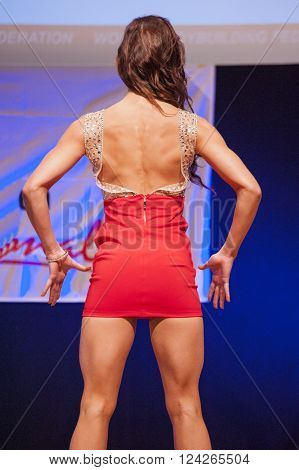 MAASTRICHT THE NETHERLANDS - OCTOBER 25 2015: Female fitness model Kimberly Goethals in evening dress shows her best in championship on stage at the World Grandprix Bodybuilding and Fitness of the WBBF-WFF on October 25 2015 at the MECC Theatre