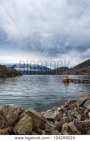 Small fishing boats by small wooden pier in a fjord in Norway