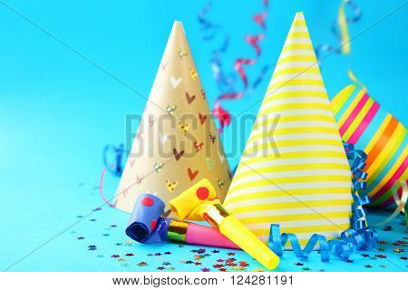 Birthday hats with serpentine streamer and noise makers on blue background