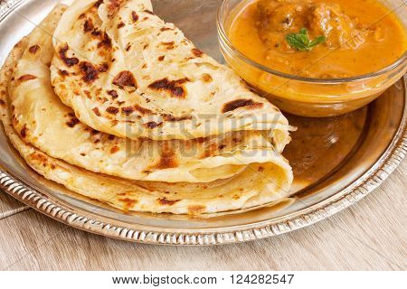 Indian layered Paratha roti kerala porotta with chicken curry on the side