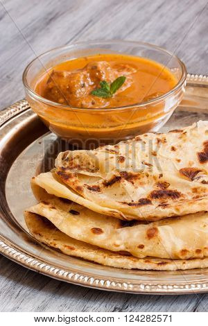 Indian layered Paratha roti kerala porotta with chicken curry on the side