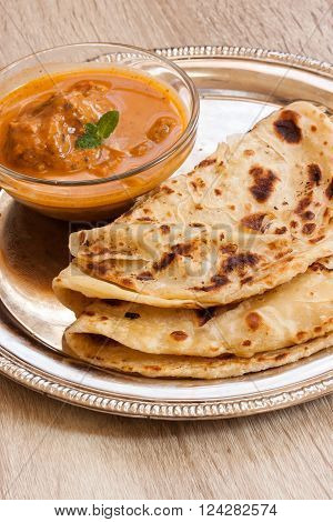 Indian layered Paratha roti kerala porotta with chicken curry on the side