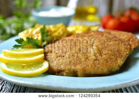Viennese schnitzel on a blue plate on rustic background.
