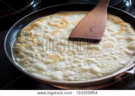 Frying pan with pancake baking on it