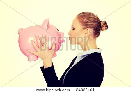 Young business woman kissing a piggybank