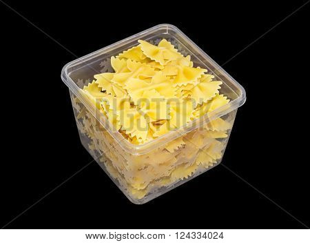 Uncooked bow-tie pasta in transparent plastic tray on a dark background
