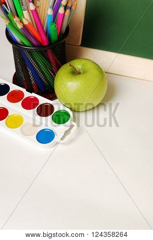 Group of school and office supplies with chalkboard watercolor paints, stack of colored pencils and markers, isolated on white