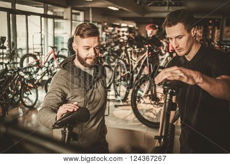 Salesman showing a new bicycle to interested customer in bike shop.