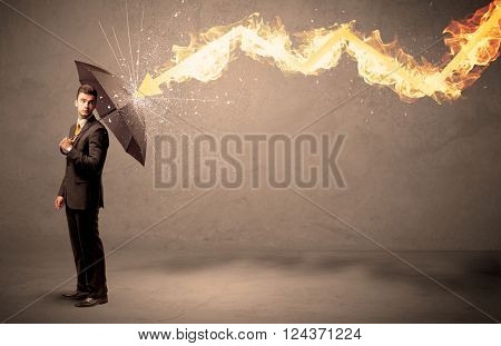 Business man defending himself from a fire arrow with an umbrella on grungy background