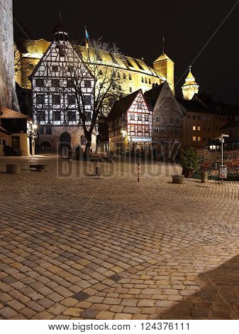 Nuremberg Germany - March 21 2016: The Castle seen from across the cobble stones of medieval square at the Durer house surrounded by old houses at night