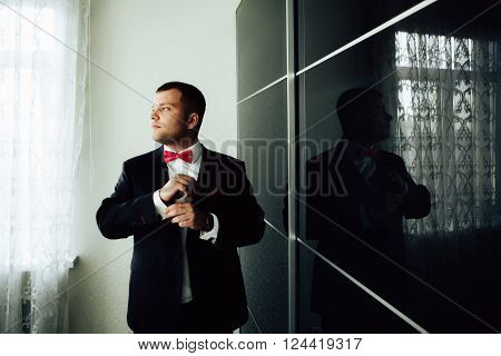 Groom in the morning on the wedding day buttoning cuffs his hands on his suit
