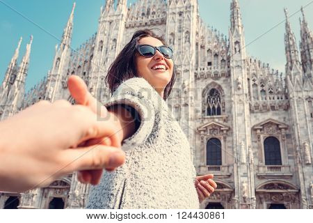 Smiling woman hold his boyfriend hand on Duomo di Milano background