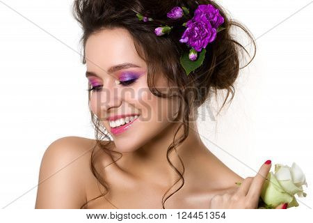Portrait of young beautiful female holding white rose with violet cloves in her hair. Bright spring or summer modern fashion make up. Pink lips and smokey eyes. Skin care or natural cosmetics concept