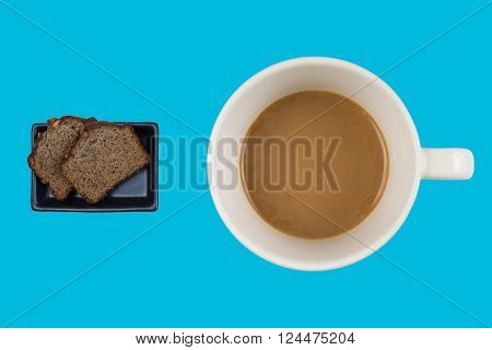 A hot dup of coffee and cake on a colored background