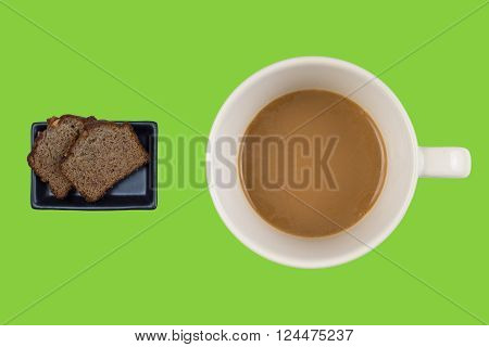 A hot dup of coffee and cake on a colored background
