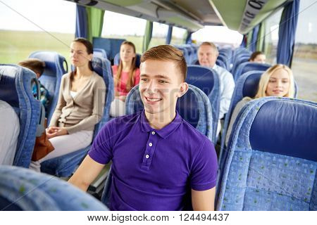 transport, tourism, road trip and people concept - happy young man sitting in travel bus or train