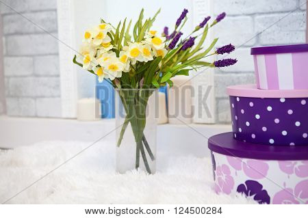 Bouquet of daffodils in a vase of glass with gift boxes in the interior of the round