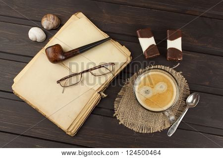 Old books, eyewear and cup of coffee on a dark wooden table. Reading vintage old book and coffee. Relax with a book and a good coffee.