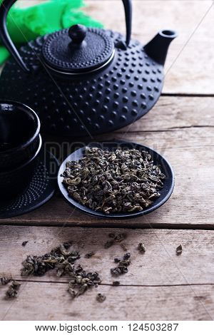 Green tea in bowl and traditional asian tea set on aged wooden background. Selective focus is on tea.